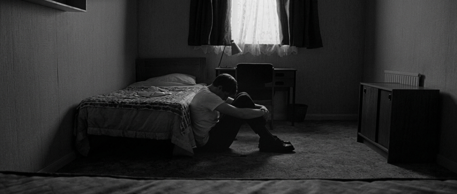 Man sitting quietly with a reflective expression, carrying the weight of emotions he was taught to hold in silence